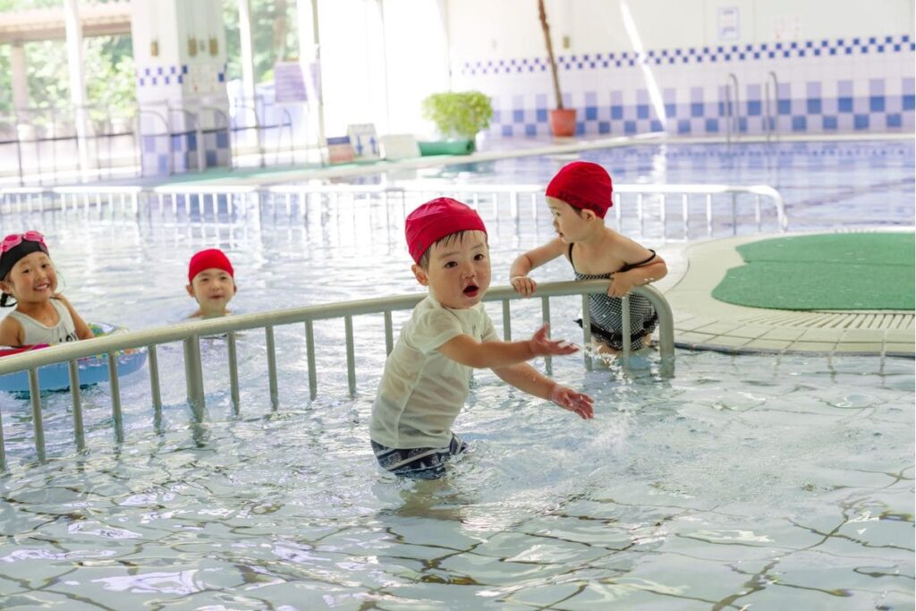 水深が浅いプールで遊ぶ水着の幼児４人