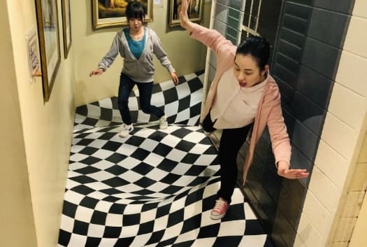 錯覚を利用した屋内遊び場を歩く女性2人の写真