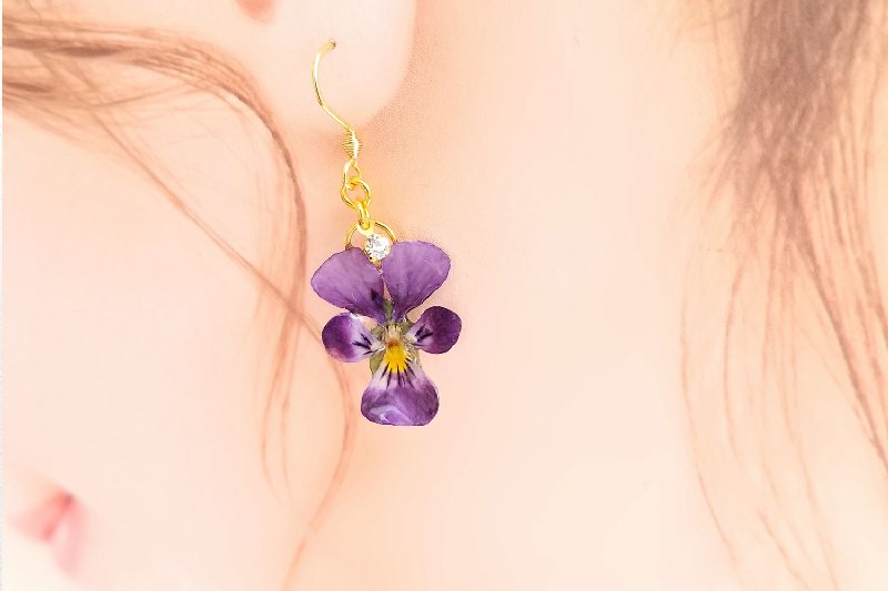 紫の花のピアスをした女性の写真