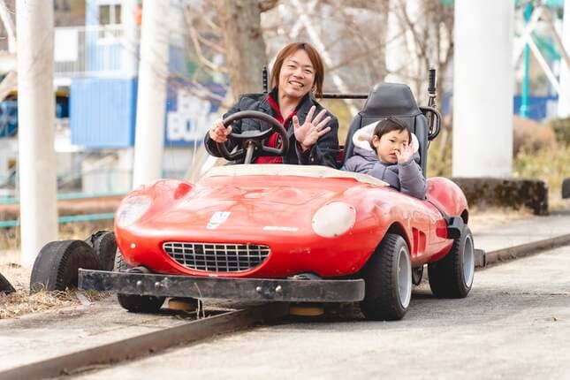 赤いゴーカートに乗るパパと息子の写真