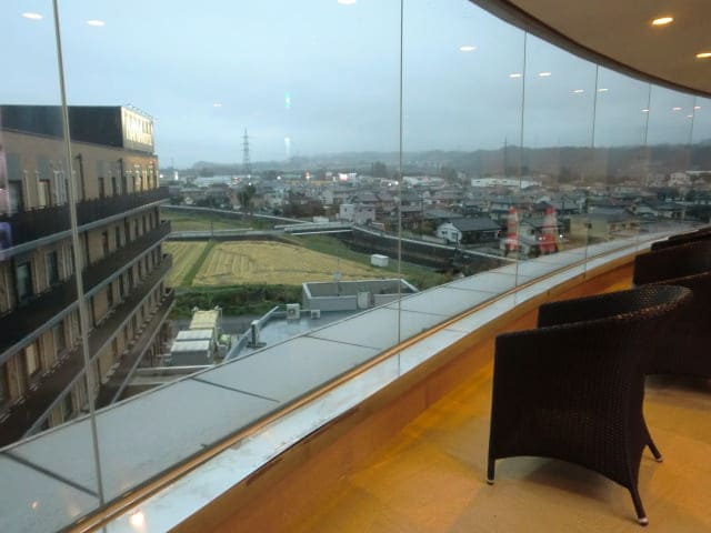 花湯スカイテルメリゾート上階窓からの景色 雨の日の夕方 ホテル裏側・民家・田んぼが見える