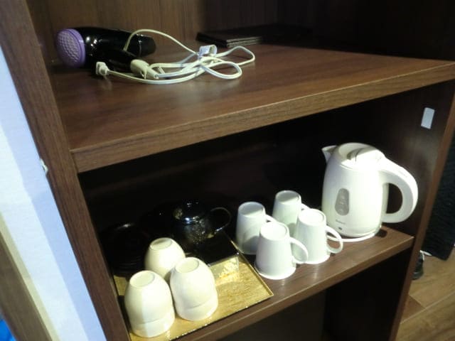 茶色の仕切り棚の写真 上の棚にドライヤー、下の棚に白いコップとポット