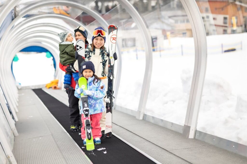 湯沢高原パノラマパークのベルトリフトに乗るスキーウエア姿の母子の写真