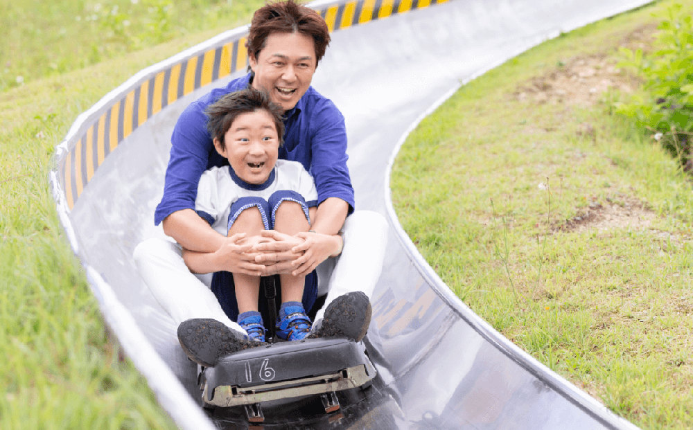 湯沢高原パノラマパークでボブスレーを楽しむ父子の写真