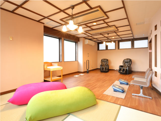 休憩所内に黒いマッサージチェア2台、足つぼマッサージ踏み台2台、オムツ替え台が用意されている写真