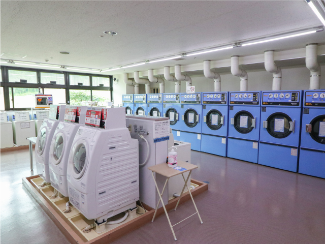 青いコインランドリーが10個と、手前に乾燥機が3台設置されたコインランドリーコーナー