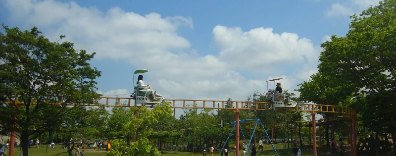 青空の下、サイクルモノレールに乗って空中散歩する写真