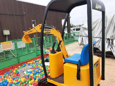 黄色のショベルカーがボールのプールにたくさん入っているカラフルボールをすくおうとしている写真