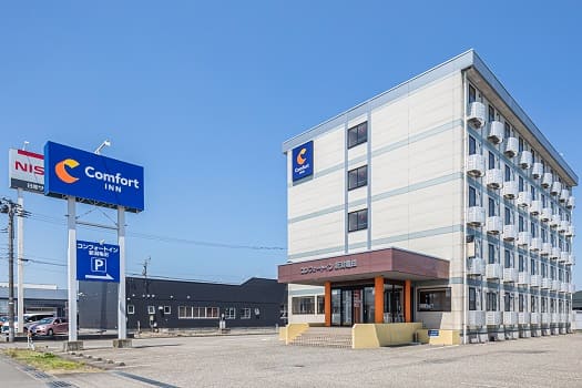 コンフォートイン新潟亀田を左斜め前から撮影した全景写真　青いホテル名の看板もある