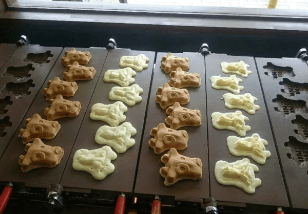 牛の顔の形をした茶と白のMoumou焼を鉄板上で焼いている写真