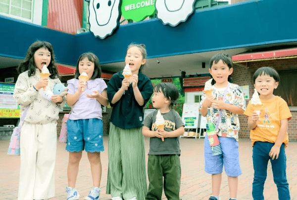 伊香保グリーン牧場の入場口前に６人の子ども達が横に並びソフトクリームを食べている写真