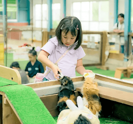 伊香保グリーン牧場　ふれあいハウス　モルモットにえさやりする少女の写真