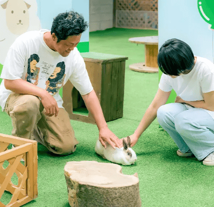伊香保グリーン牧場　ふれあいハウス　内でうさぎとふれあいをするカップルの写真